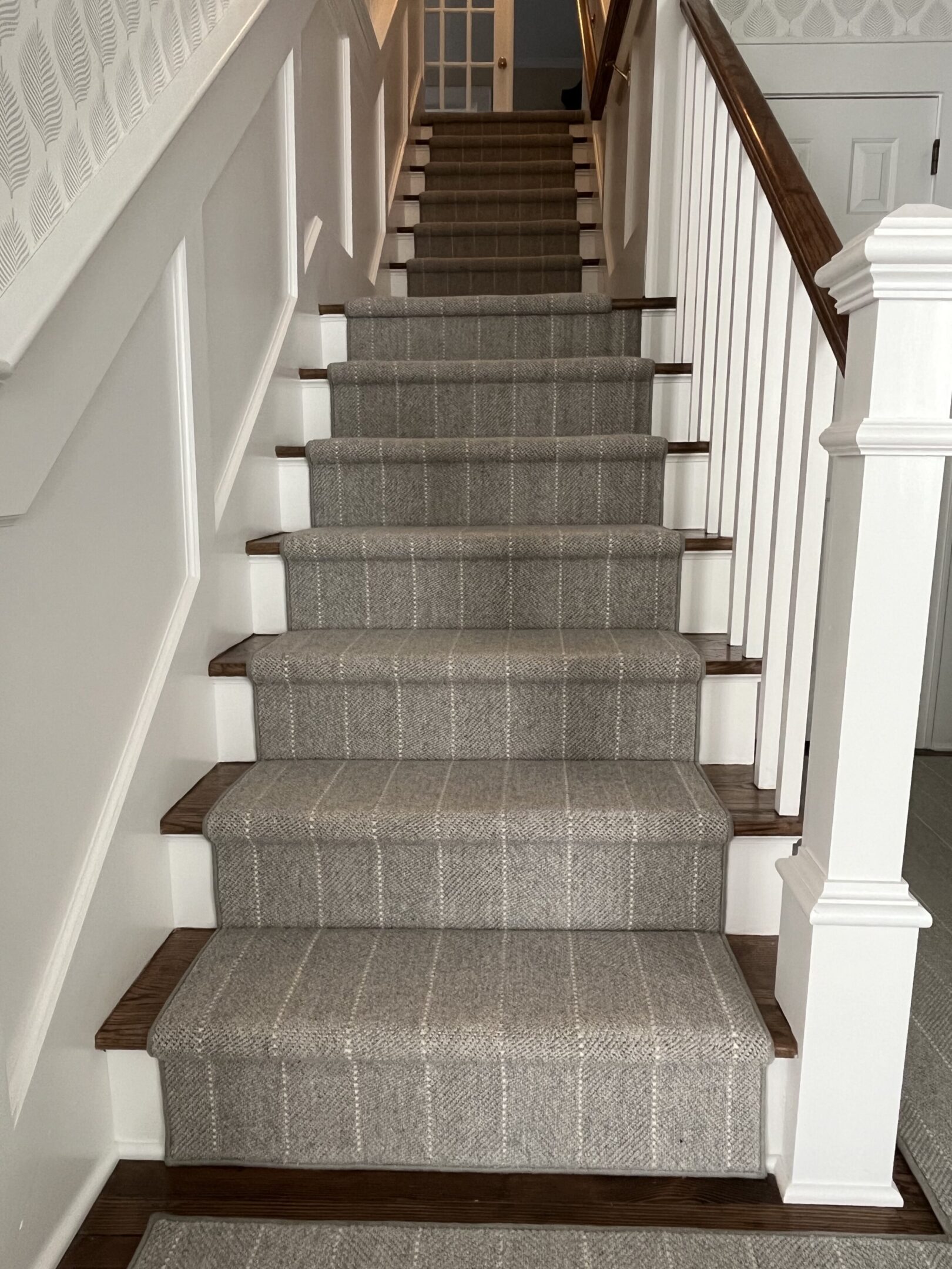 A staircase with a carpet runner on the bottom of each step.