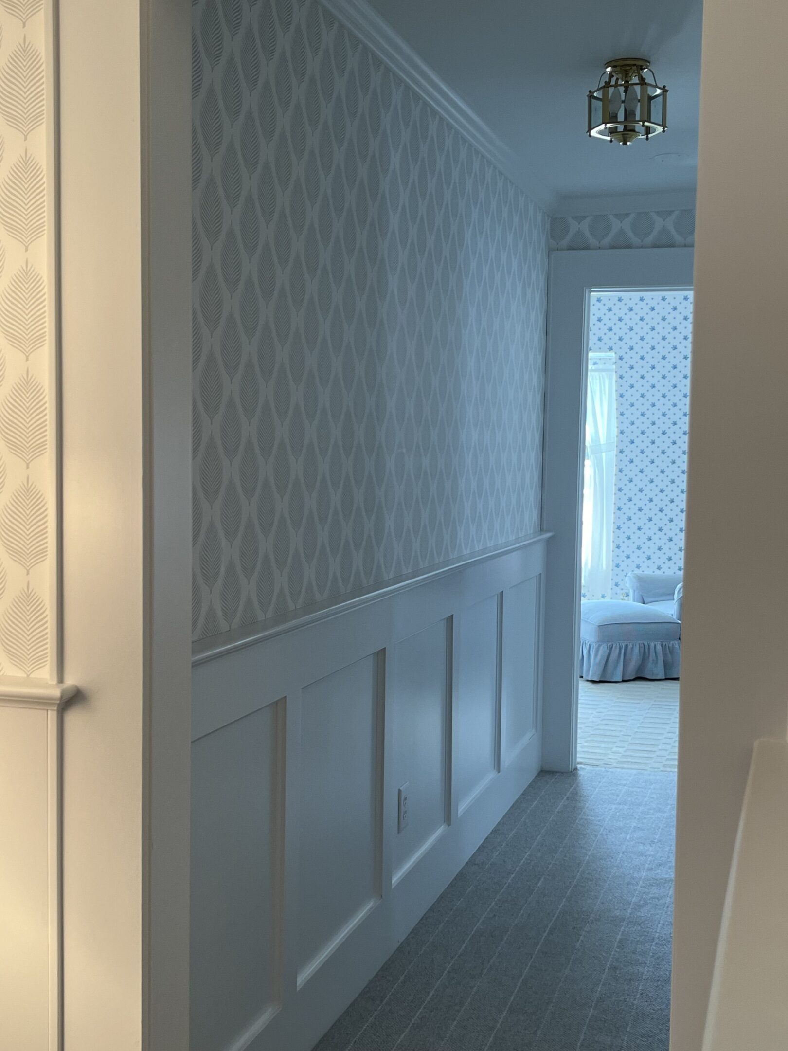 A hallway with white walls and a patterned wall paper.