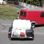 Trailer with equipment near a red van.