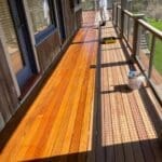 Person staining wooden deck with brush.