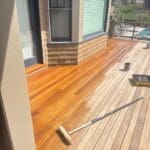 Wooden deck being stained near a house.
