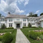 Large white house with lush green lawn.