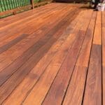 Worker staining outdoor hardwood deck boards