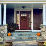 Front porch with pumpkins and wooden door.