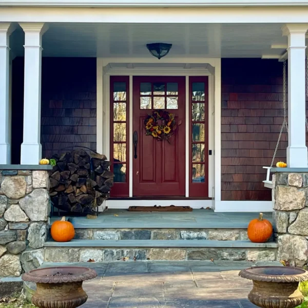 Front porch with pumpkins and wooden door.